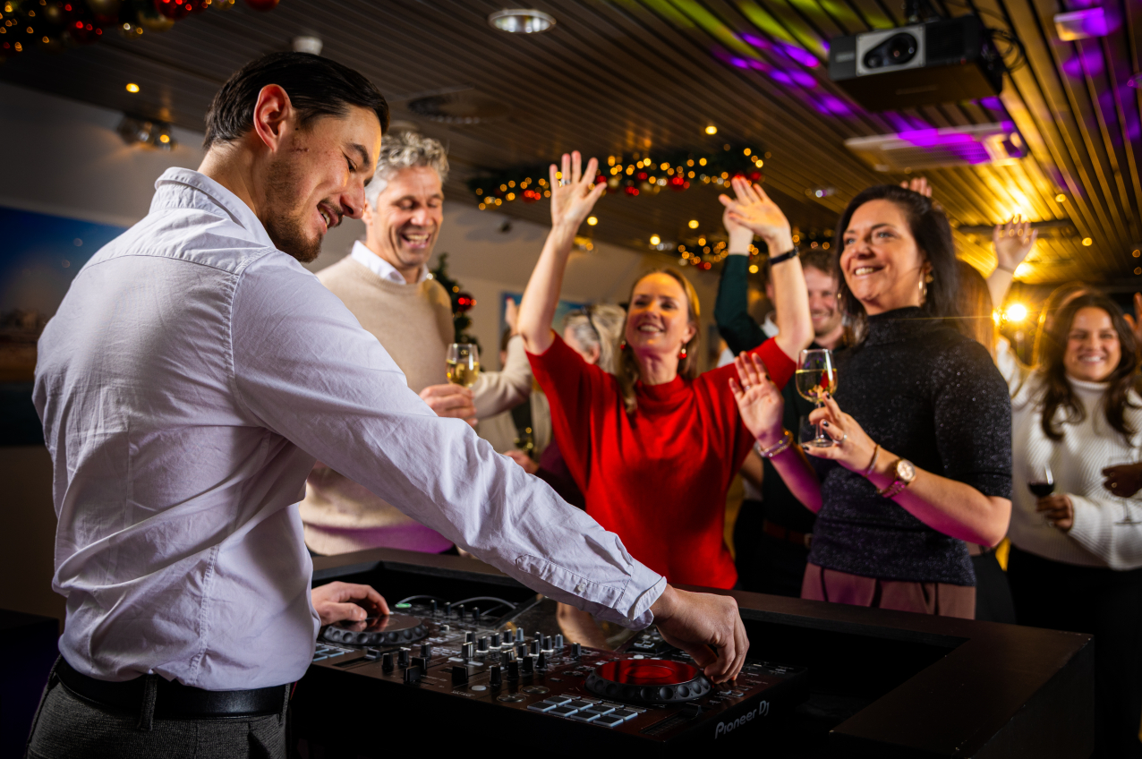 Feestende mensen voor dj-booth in versierde zaal in Madurodam